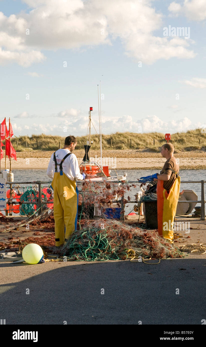 Fishermen cleaning fishing nets on Mudeford Quay Stock Photo Alamy