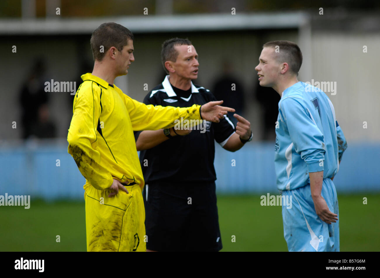referee tries to settle dispute between two opponents Stock Photo