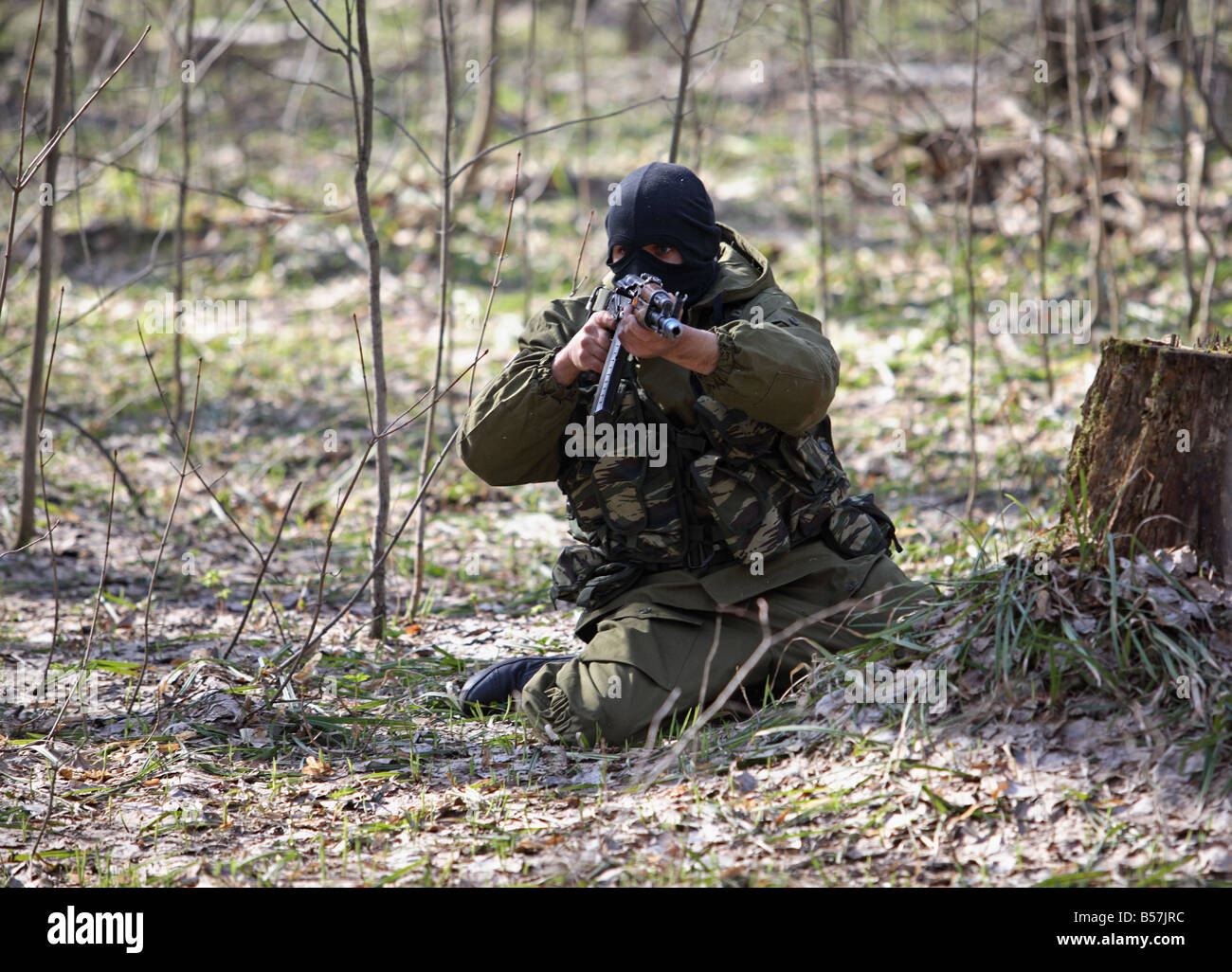 Man firing a kalashnikov ak47 assault rifle dressed as a terrorist Stock Photo