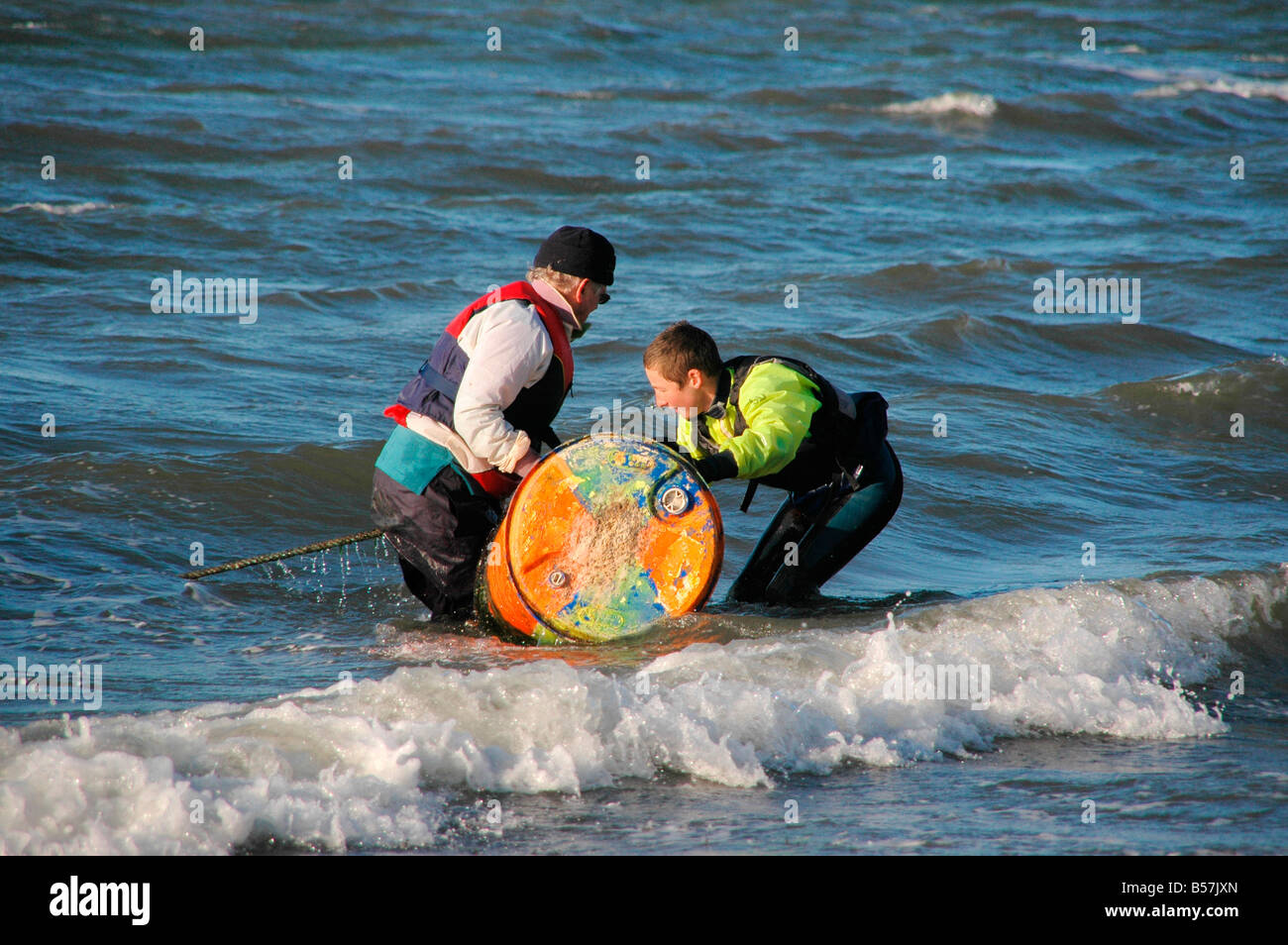 A boy and man bring in the buoys from the sea at the end of the sailing / dinghy season in Scotland. Stock Photo