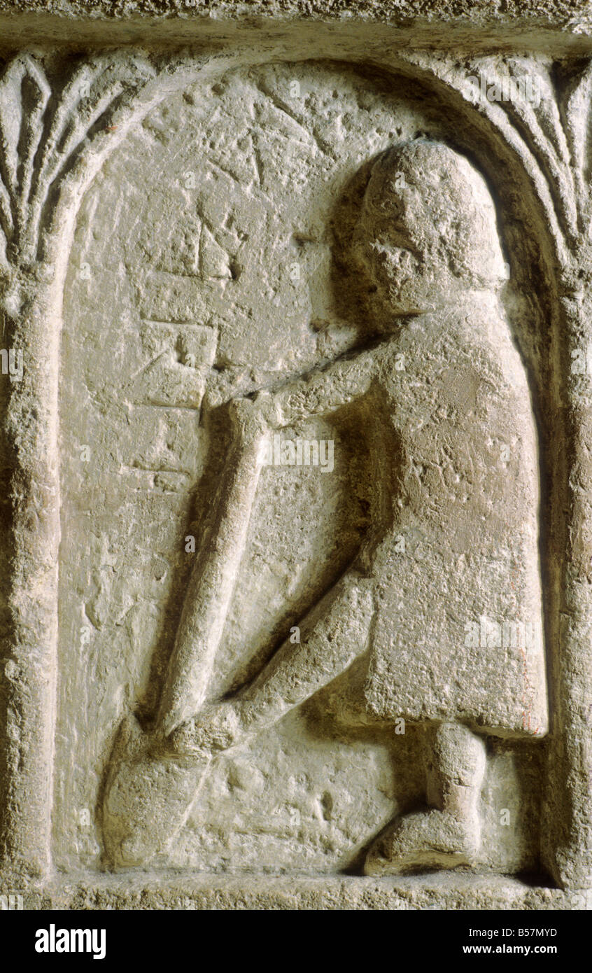 Burnham Deepdale Norman Font detail March Digging soil with spade Labour of the Month 12th century carving Romanesque Norfolk Stock Photo