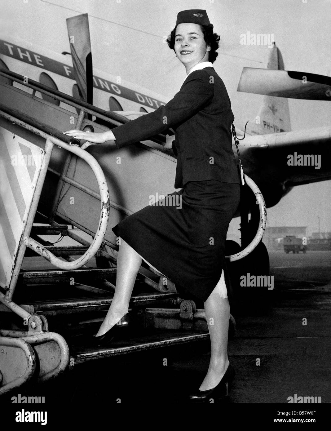 Lady Douglas, wife of BEA's Chairman, persuaded her husband to give an order for three inches to be sniped off the skirts of the company's 700 air girls. Some of the girls rebelled against the new hemlines. But now, K.L.M. Royal Dutch Airline, have beaten B.E.A. – by a short skirt. The company this morning issued to their girls an entirely new uniform in midnight blue serge. The skirt length is just blow the knee and there’s and open pleat at the back. Here, 24-year-old K.L.M. receptionist Pamela Gregson, is seen in her new show-a-leg uniform. January 1959 P004607 Stock Photo