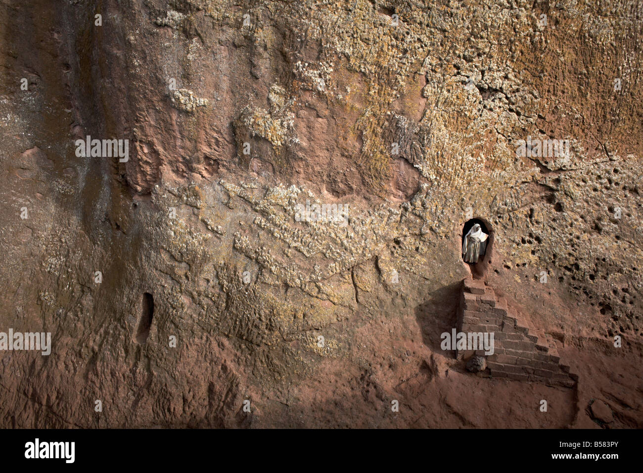 A woman emerges from a tunnel leading to the rock-hewn church of Bet Amanuel, in Lalibela, Ethiopia, Africa Stock Photo