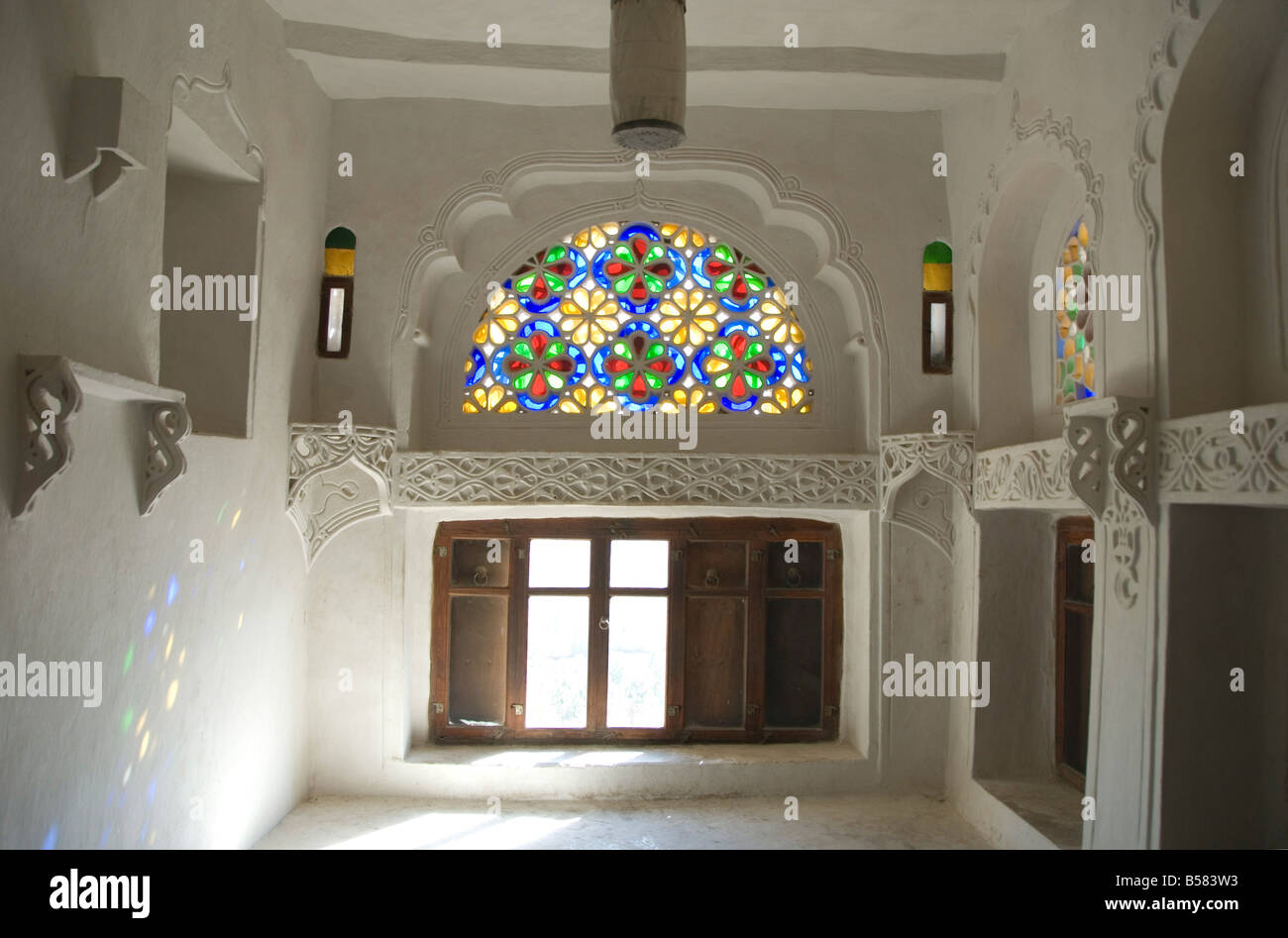 Traditional upper window of stained glass in upstairs room within the Dhar Alhajr, Wadi Dhahr, near Sana'a, Yemen Stock Photo