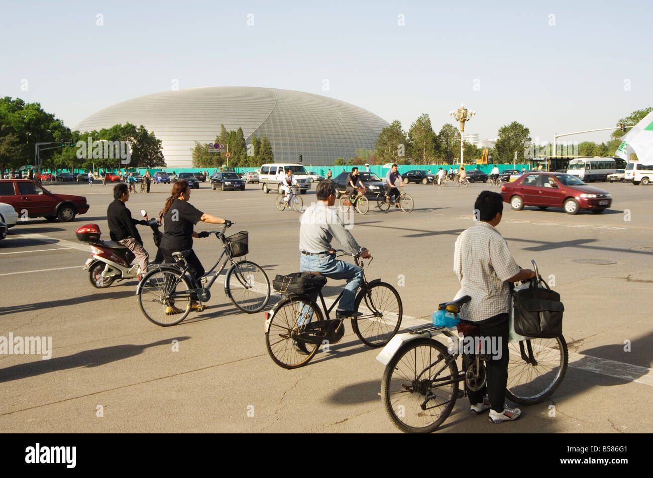 The National Theatre designed by the French architect Paul Andreu, and cyclists commuting in central Beijing, Beijing, China Stock Photo