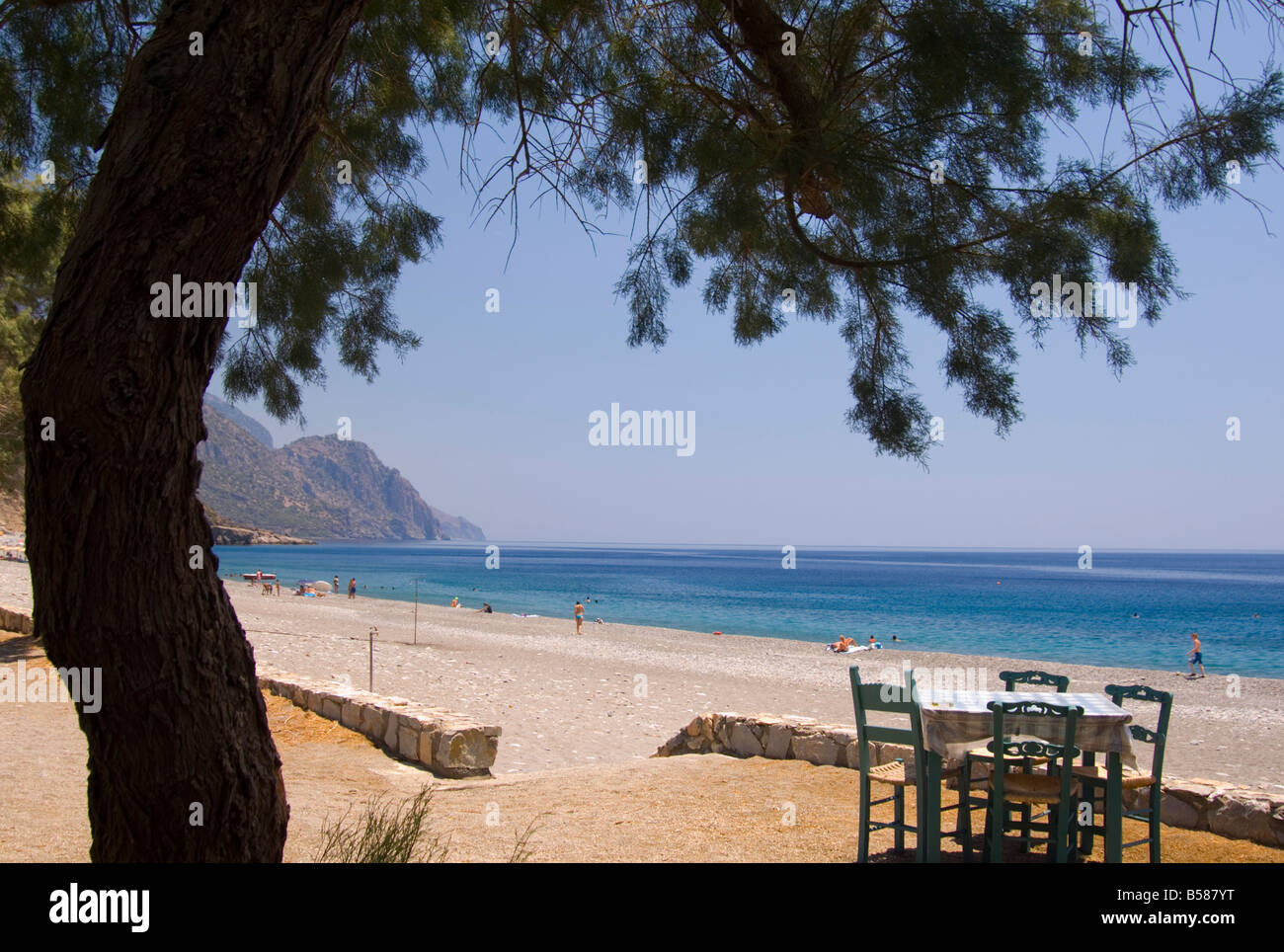 A taverna table facing the sea and pebble beach in Sougia on the south coast of Crete, Greece, Europe Stock Photo