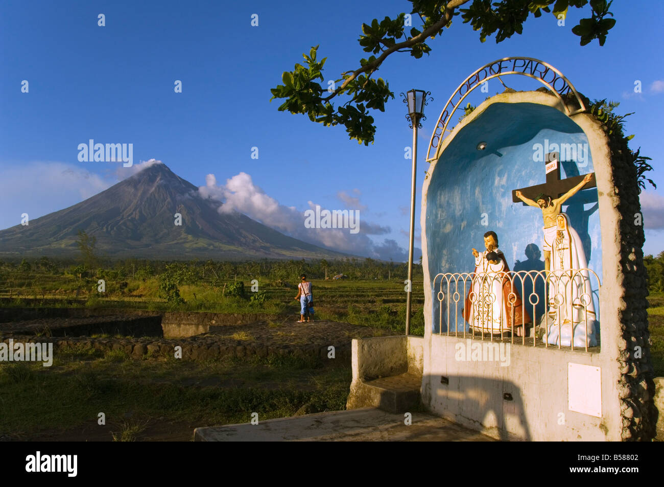 Volcanic cone plume of smoke of Mount Mayon 2462m & grotto/wayside shrine Bicol Province Luzon Island Philippines Southeast Asia Stock Photo