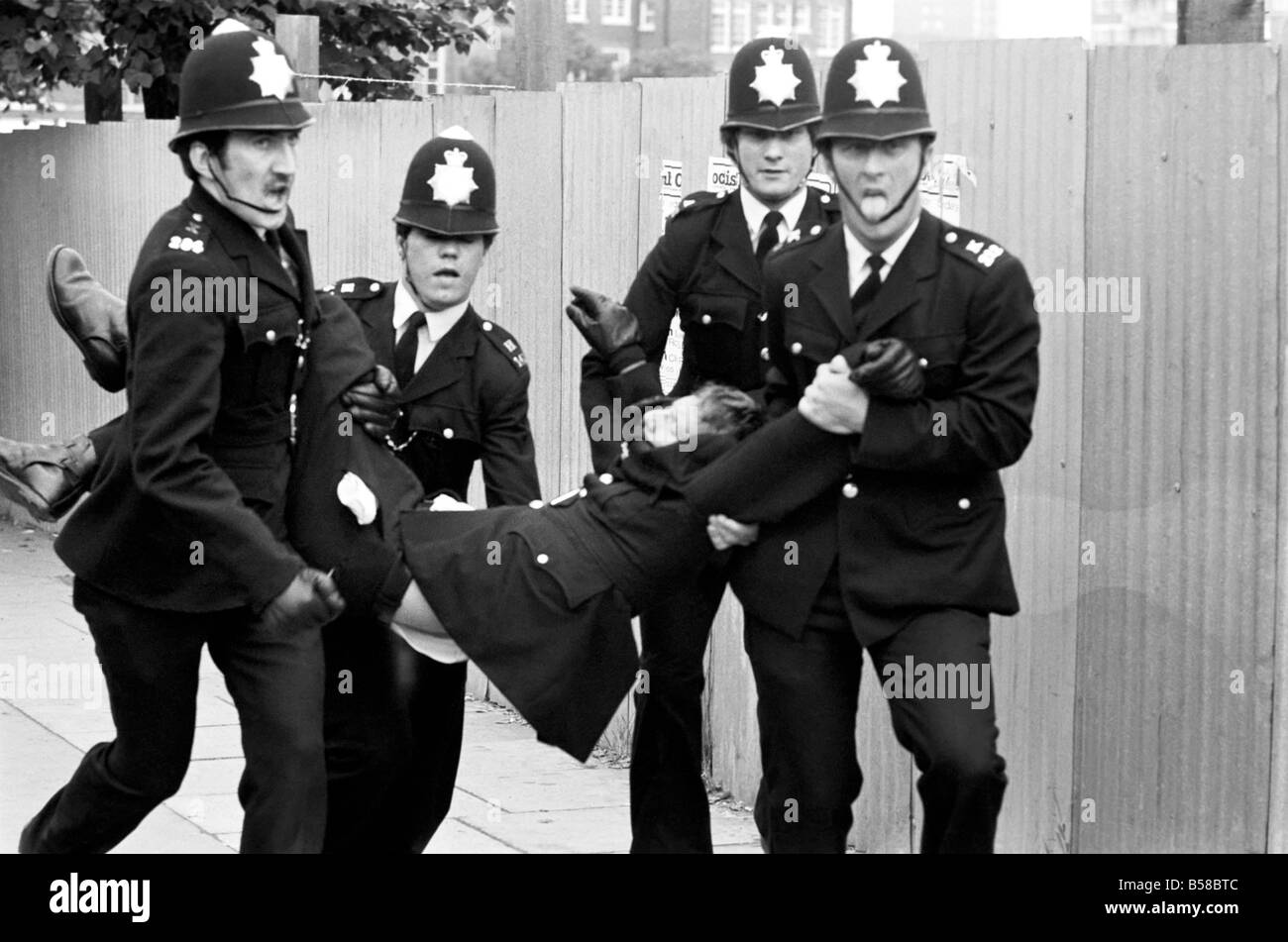 Lewisham Riot 1977: An injured policeman is carried away from the Lewisham riot by colleagues. The riot was sparked by a National Front march through the centre of town, which was confronted by a left wing counter demonstration. August 1977 77-04357-009 Stock Photo