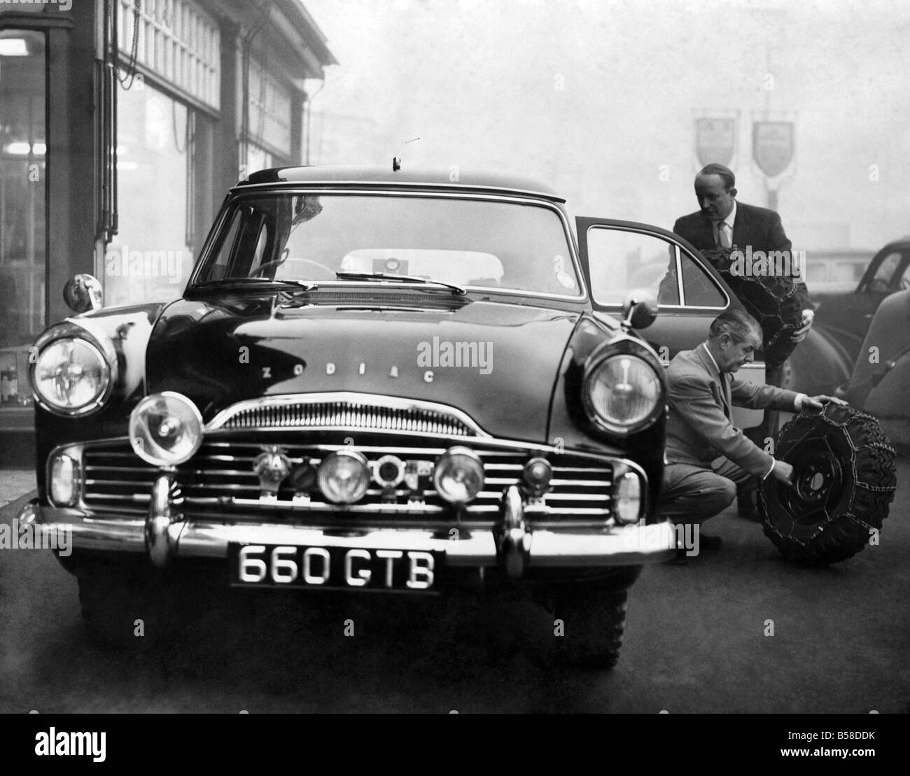 Loading the Ford Zodiac estate car, in which he will compete in the Monte Carlo rally, with special chained wheels for the Arctic conditions expected are Mr. C.A. Bennett, General Works Manager of Quick's of Manchester, (nearest camera), and Mr. Norman Quick the Managing Director of the firm, who will be one of the drivers. January 1959 P005818 Stock Photo