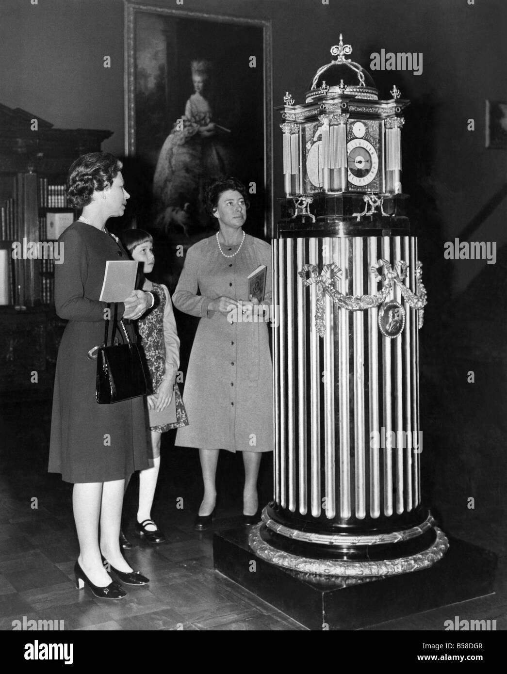 H.M. The Queen H.R.H. Princess Margaret, and Lady Sarah Armstrong Jones looking at a four faced Astronomical clock, made in 1768 by Christopher Pinchbeck for King George III. The clock case was designed by Sir William Chambers, assisted by the king. Picture at rear is Gainsborough of queen Caroline. November 1974 P006317 Stock Photo