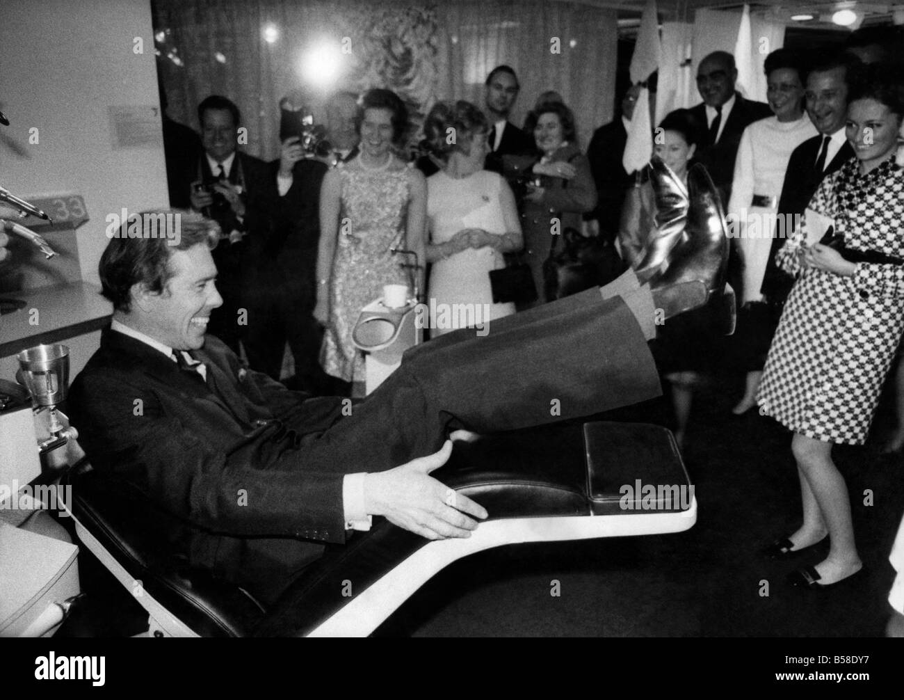 Lord Snowdon trying out the motorised reclining dentist chair at the exibition, watched by Princess Margaret (partially hidden beyond Tony's feet) and on the right, Prince Albert and Princess Paola. March 1969 P007148 Stock Photo