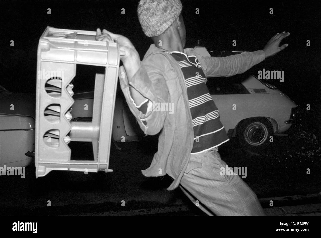 The Birmingham Riots. A demonstrator throws a milk crate at a police car during the violence at the National Front meeting in Ladywood Birmingham tonight (Monday). August 1977 77-04392-012 Stock Photo