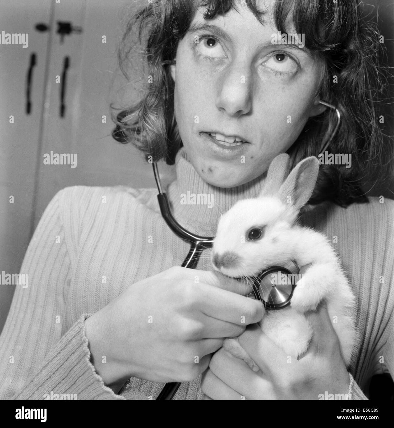 Animal: Cute: Bunny: It was a moment of tender wonderment, when a child can hear the rhythmic beat of a tiny heart. The few weeks old white rabbit at the ChildrensÍ Zoo, Crystal Palace, London is just one of a litter born there, and soon to be heading for new homes. December 1976 76-07571-002 Stock Photo