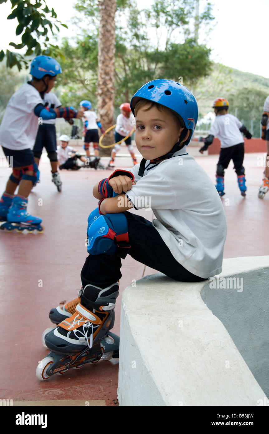 SCHOOL BOY SPORTS TEAM ALONE PENSIVE Junior schoolboy sitting in playground  sidelined during rollerblade game wearing full rollerblade safety clothing  Stock Photo - Alamy