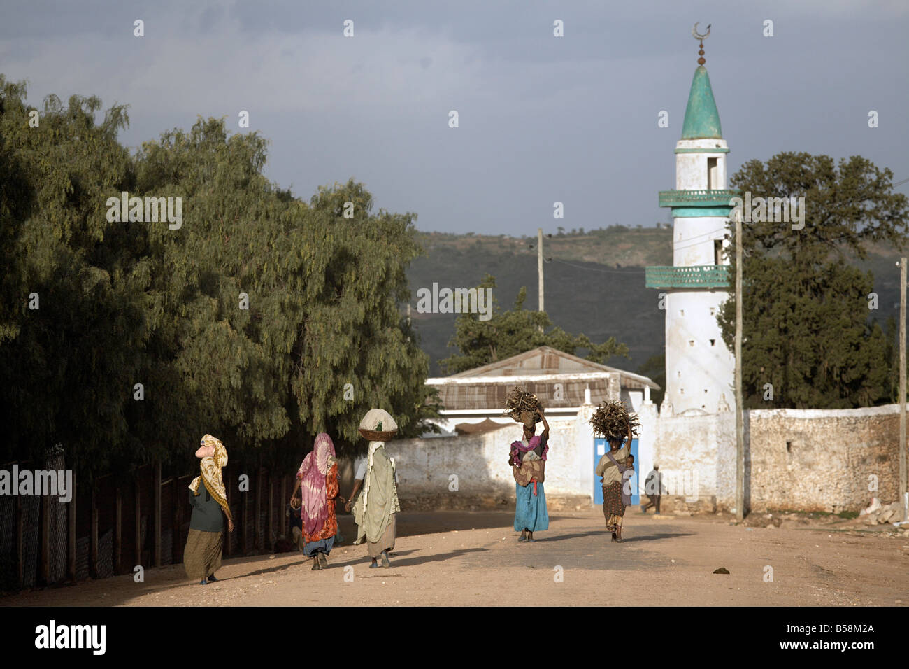 Women carry their wares on their heads, near a mosque in the city of Harar, Ethiopia, Africa Stock Photo
