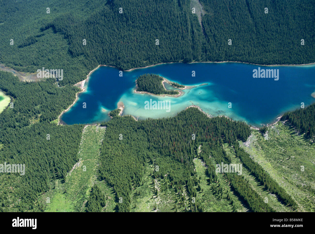 Lake in Rocky Mountains near Banff with avalanche damage visible in bottom half of picture Alberta Canada North America Stock Photo