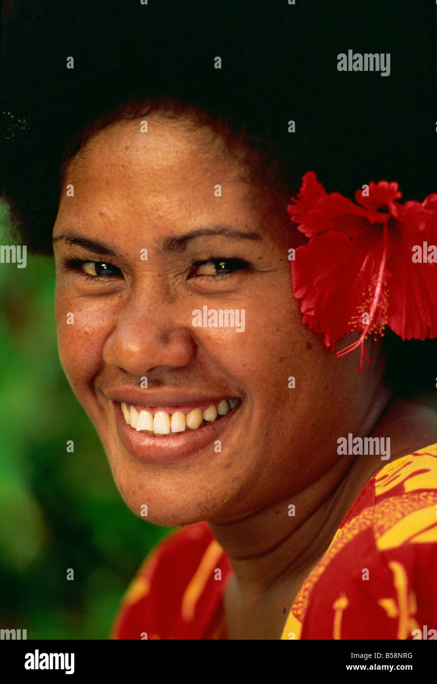 Portrait of a Melanesian girl with a red hibiscus flower in her hair on ...