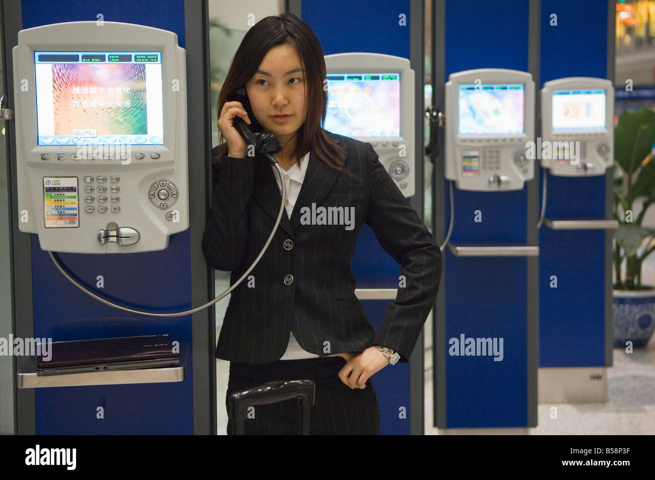 A Chinese business woman making a telephone call at Beijing Capital Airport, Beijing China Stock Photo