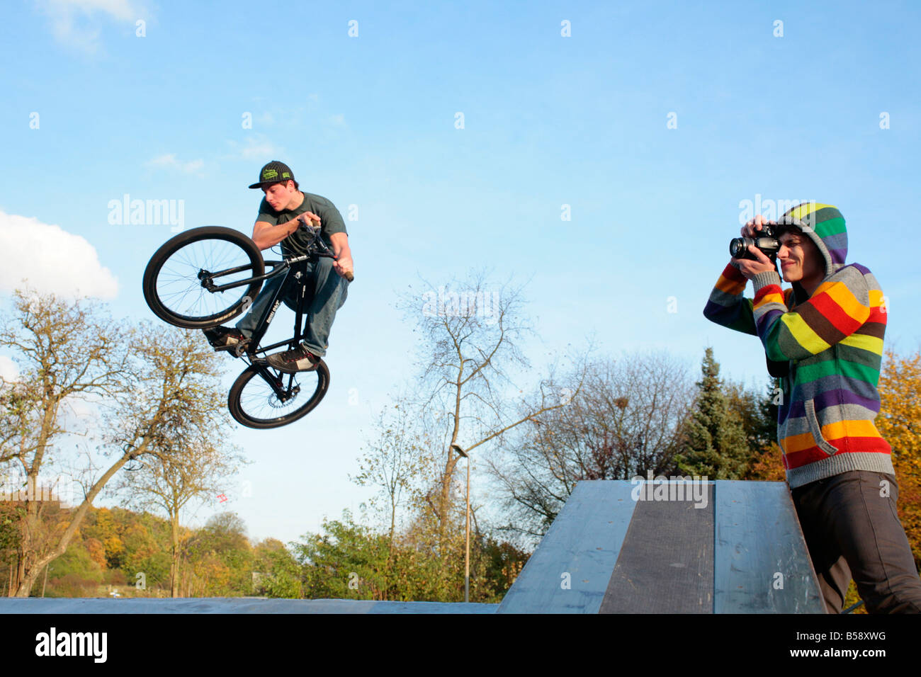 young man jumping with his bicycle while another one is taking photographs Stock Photo