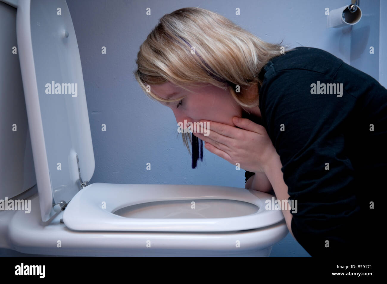 young woman teenage girl being sick vomiting into toilet bowl - morning sickness as a result of pregnancy UK Stock Photo