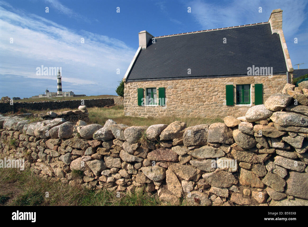 Stone wall and ancient house with the Creach lighthouse in the background on Ouessant island Brittany France G Thouvenin Stock Photo