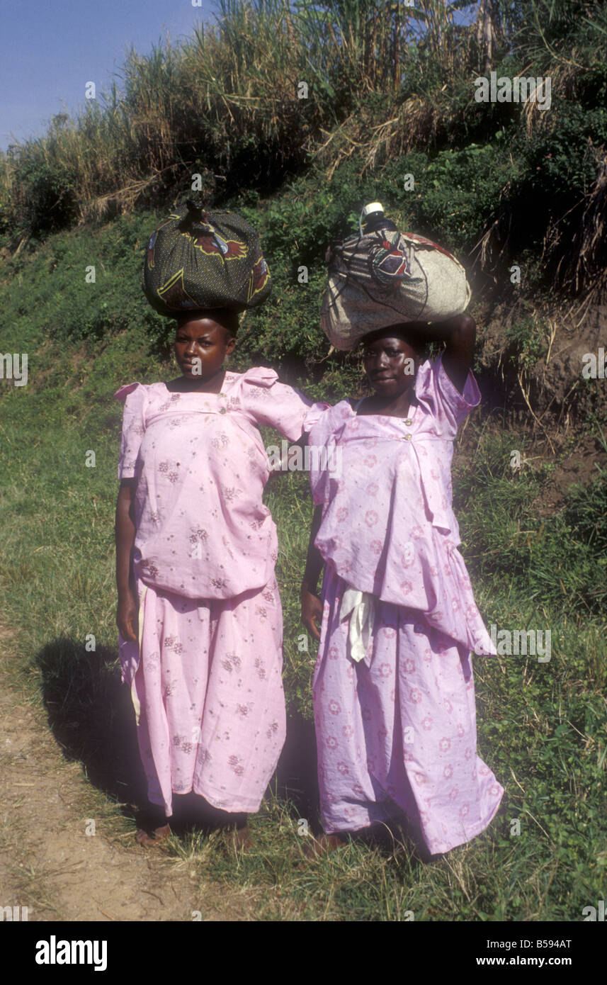 Two women carrying heavy head loads and wearing traditional long cotton ...