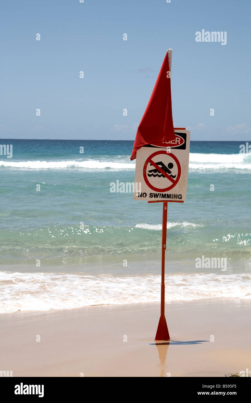 Danger No Swimming sign with red flag with sea on Cylinder Beach North Stradbroke Island Queensland QLD Australia Stock Photo