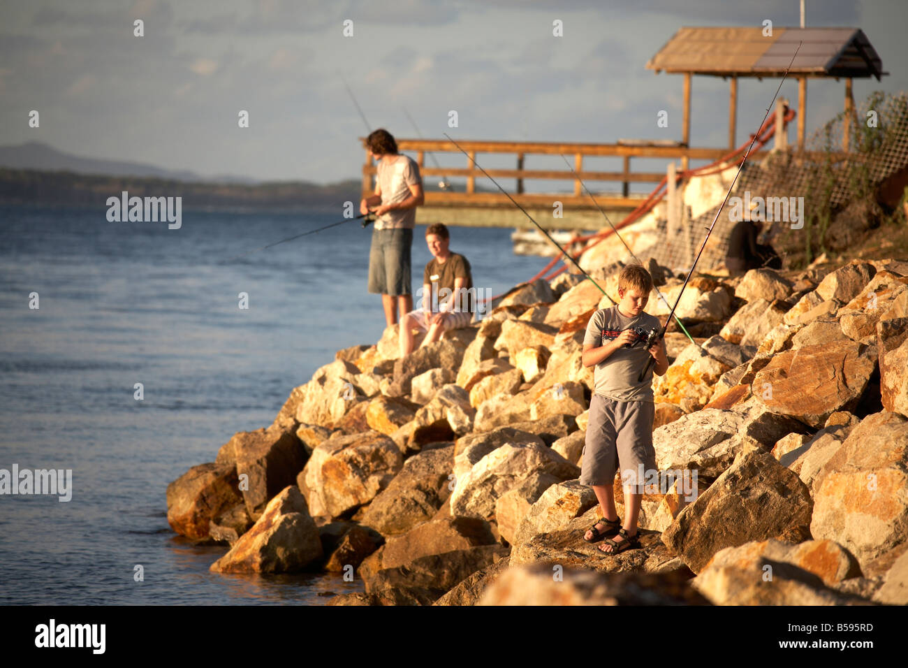 People fishing in the sea by pier at Amity Point in evening light on North Stradbroke Island
