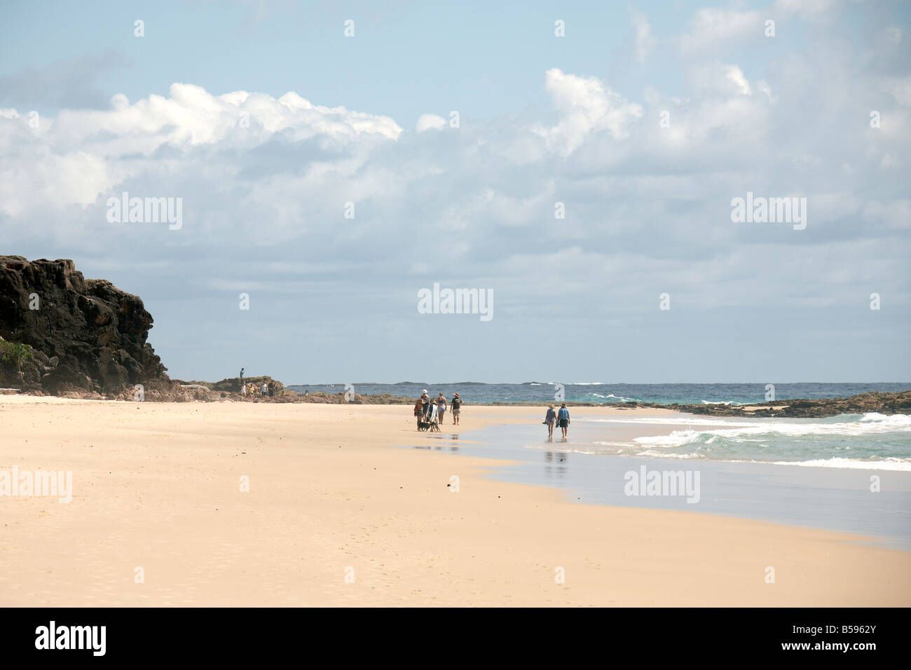 People walking by the sea on Frenchmans Beach with mackerel sky above North Stradbroke Island Queensland QLD Australia Stock Photo