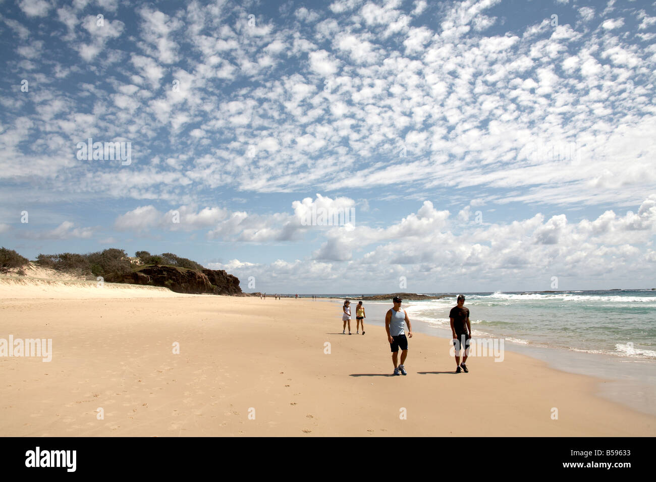 People walking by the sea on Frenchmans Beach with mackerel sky above North Stradbroke Island Queensland QLD Australia Stock Photo
