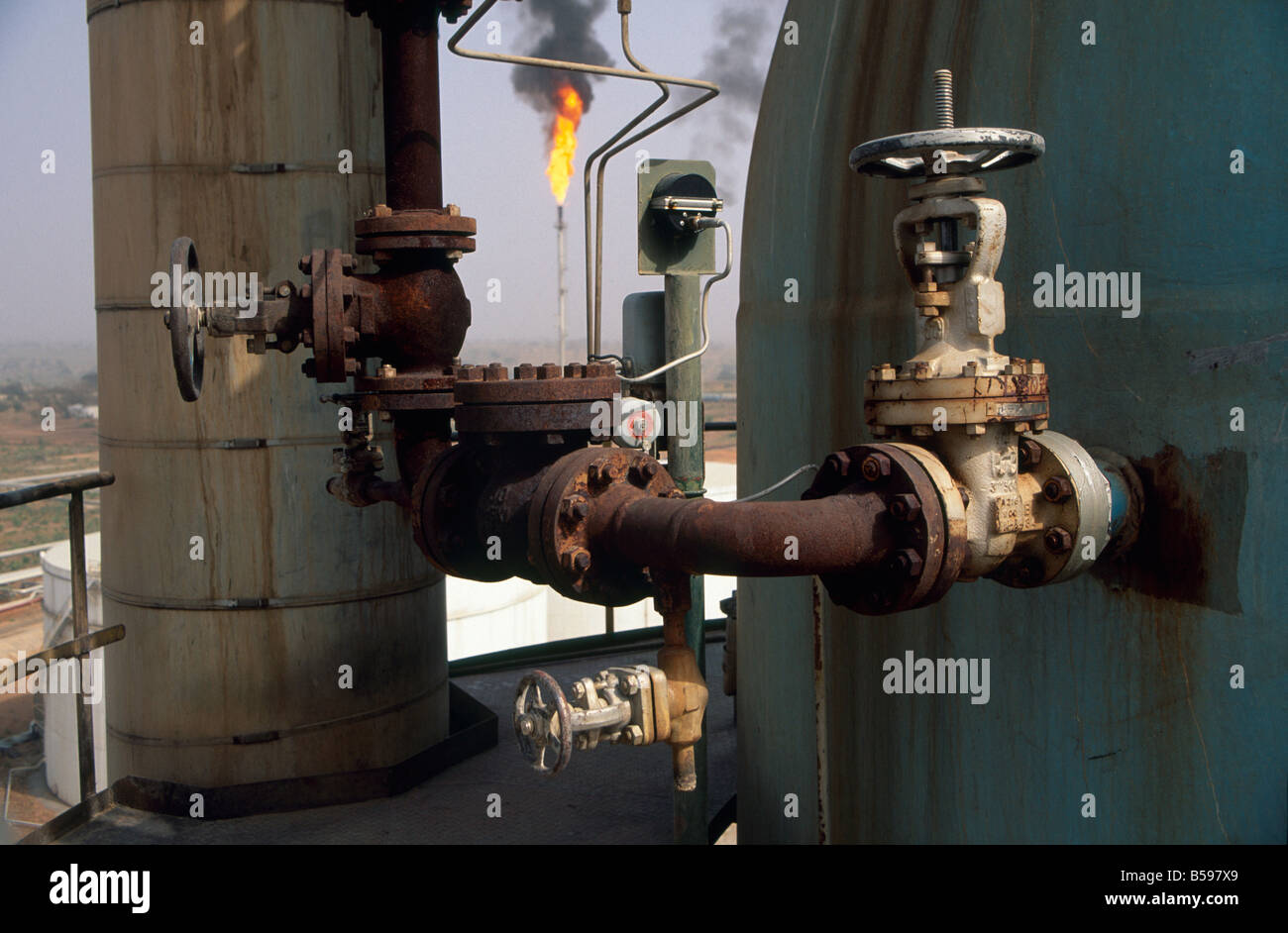 Valves with gas flare beyond in NNPC Nigerian National Petroleum Corporation oil refinery in Kaduna Nigeria Africa Stock Photo