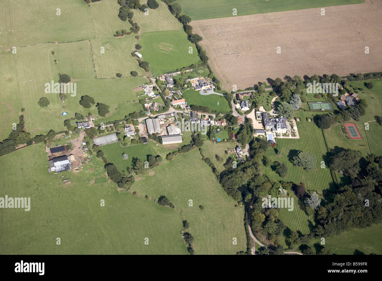 Aerial view north east of country houses farms tennis courts fields trees Little Munden Hertfordshire England UK High level obli Stock Photo