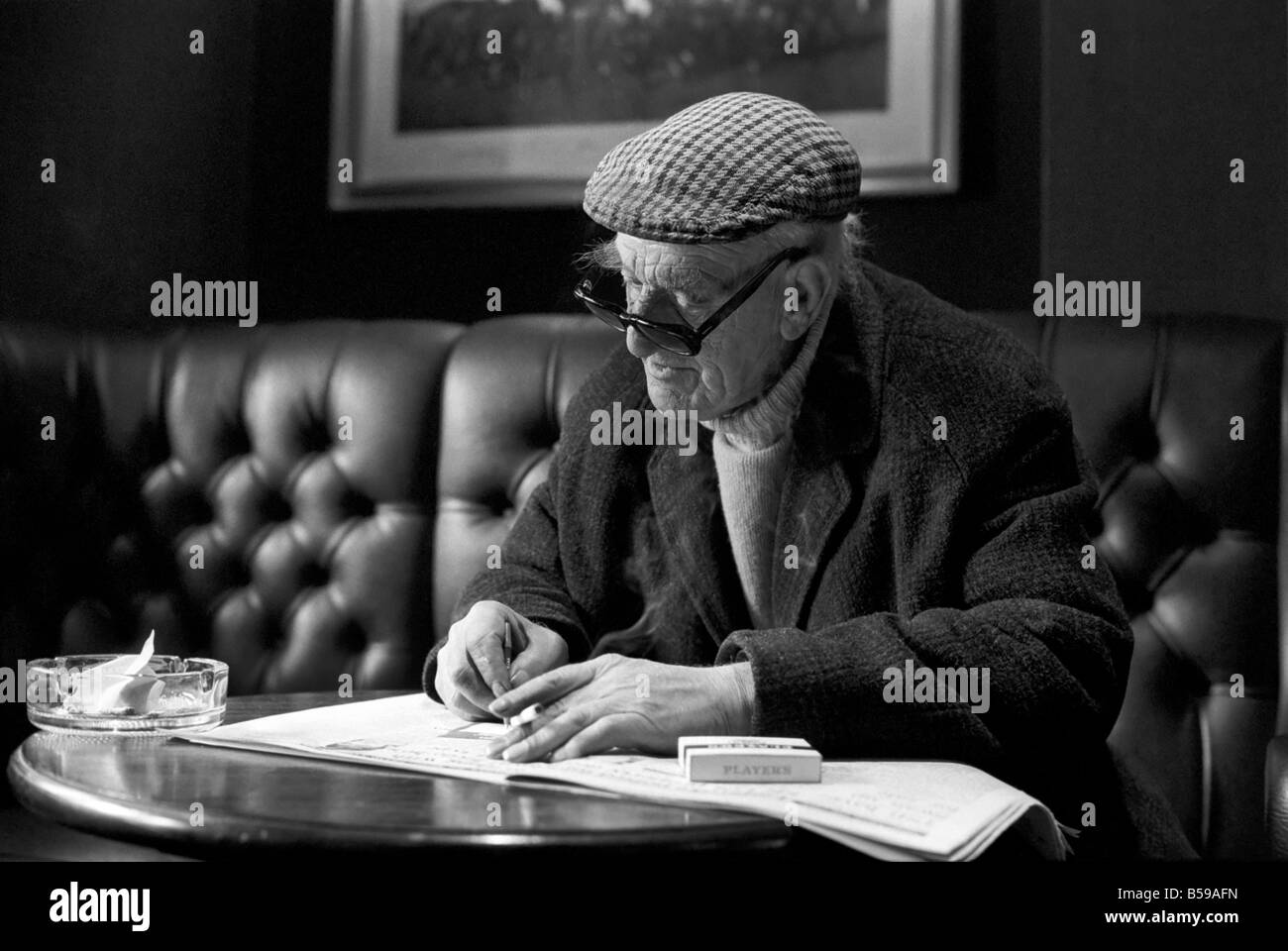 Pensioner: Elderly man filling his pools coupon whilst enjoying a cigarette and a pint in his local pub. PM 81-01800a-002 Stock Photo