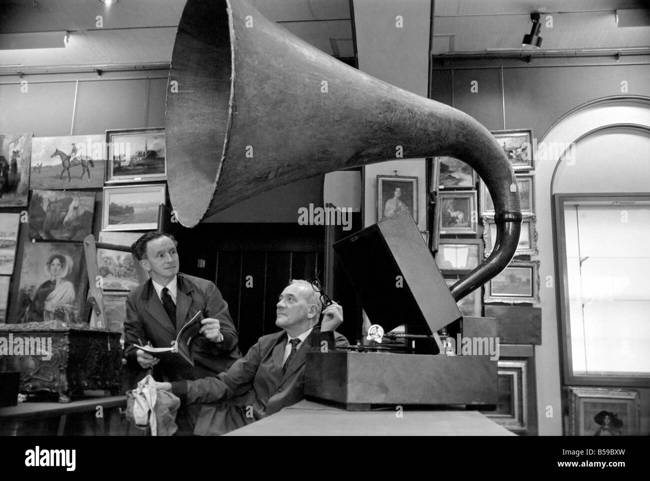 The sound of music. It was a case of give me the good old days for the assistants at Sotheby's Belgravia Showrooms in Motcomb Street, W.1. as old timers listened to the music of their youth emerging from the massive 2ft. 9in. diameter papier mache horn of an E.M. Ginn Expert Senior 'Oversize' Gramophone with Garrard electric motor, E.M.G. expert reproducer and 12 inch turntable in a light oak case which is one of the items that will be going on sale at Sotheby's on the 9th April 1975. It is expected to fetch between £80 and £140. April 1975 75-1748 Stock Photo