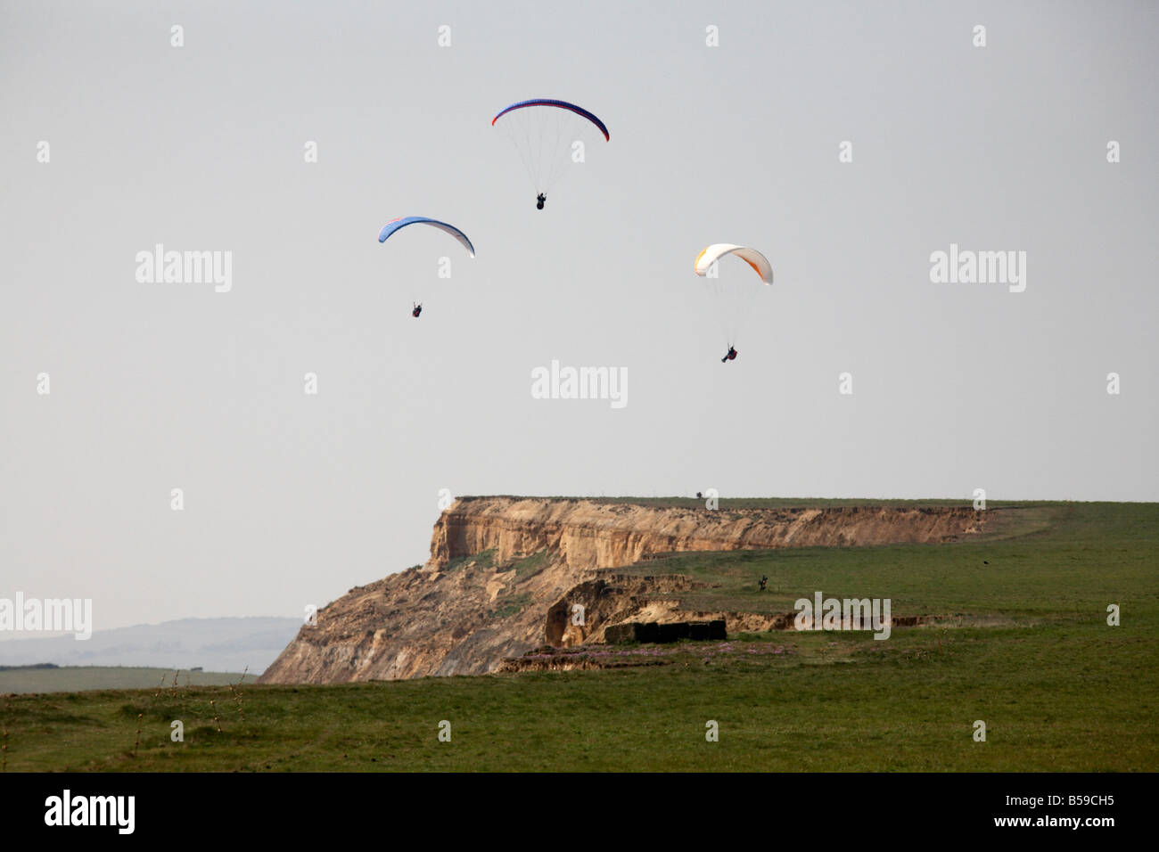 Pilots paragliding flying paragliders above Chale Bay south coast sea
