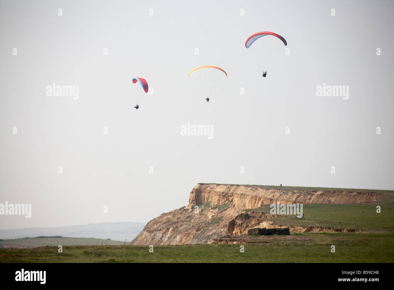 Pilots paragliding flying paragliders above Chale Bay south coast sea