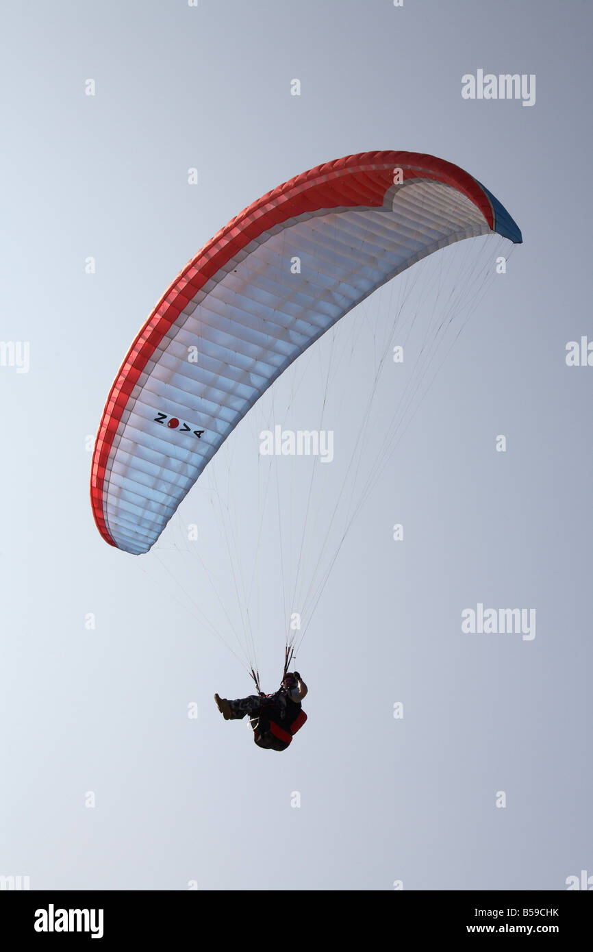 Pilot paragliding flying paraglider above Chale Bay south coast sea