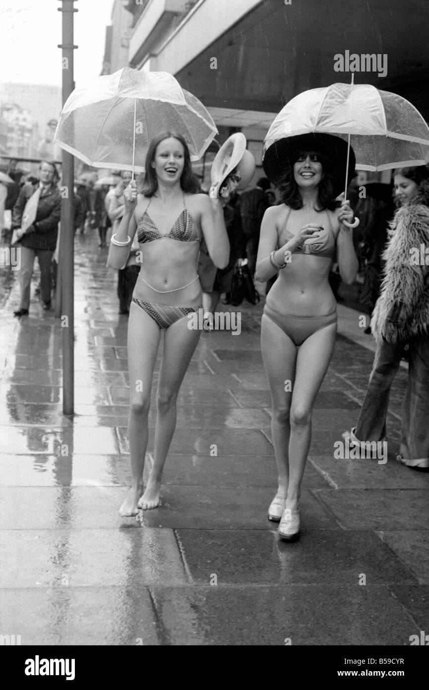 Models Wendy and Jackie seen here modeling the latest in swimwear on a wet Oxford  Street, London: Model Wendy wearing a bikini by Mitex. Available in green  or chocolate checks and Model