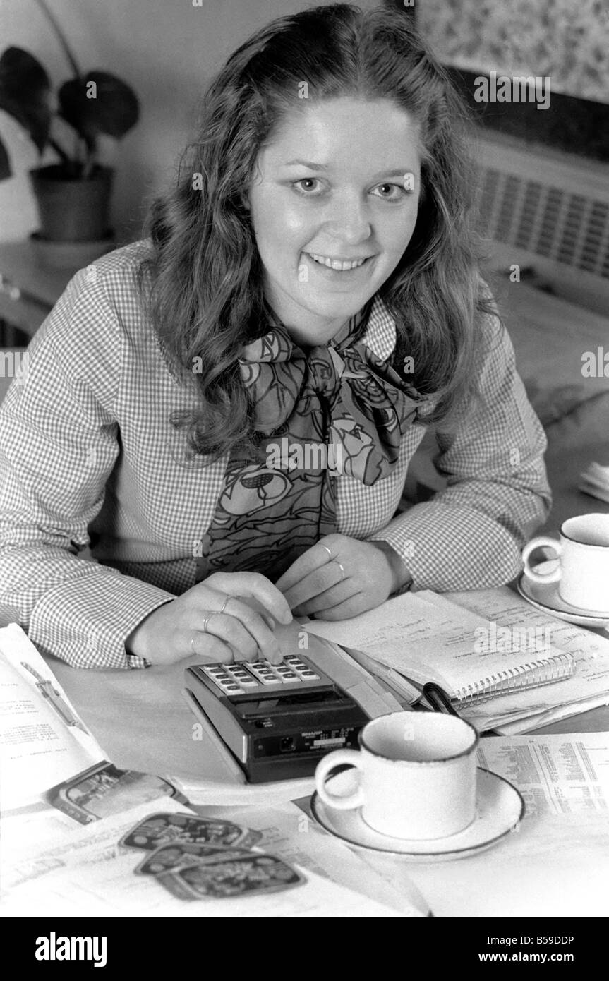 A desk covered with paper, empty coffee mugs and a calculator symbols of the busy, modern executive, and used by attractive Verity Vickers who has moved from being a secretary to an executive with Austin-Toppan Limited. ;February 1975 ;75-01070-003 Stock Photo