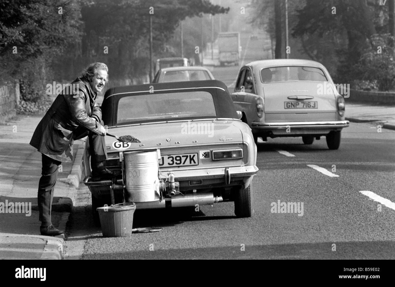 Mr. Douglas Purser who runs his Ford 1,600 c.c. Capri on Coal, is pictured shovelling anthracite into the burner. Feb. 1975 75-0 Stock Photo