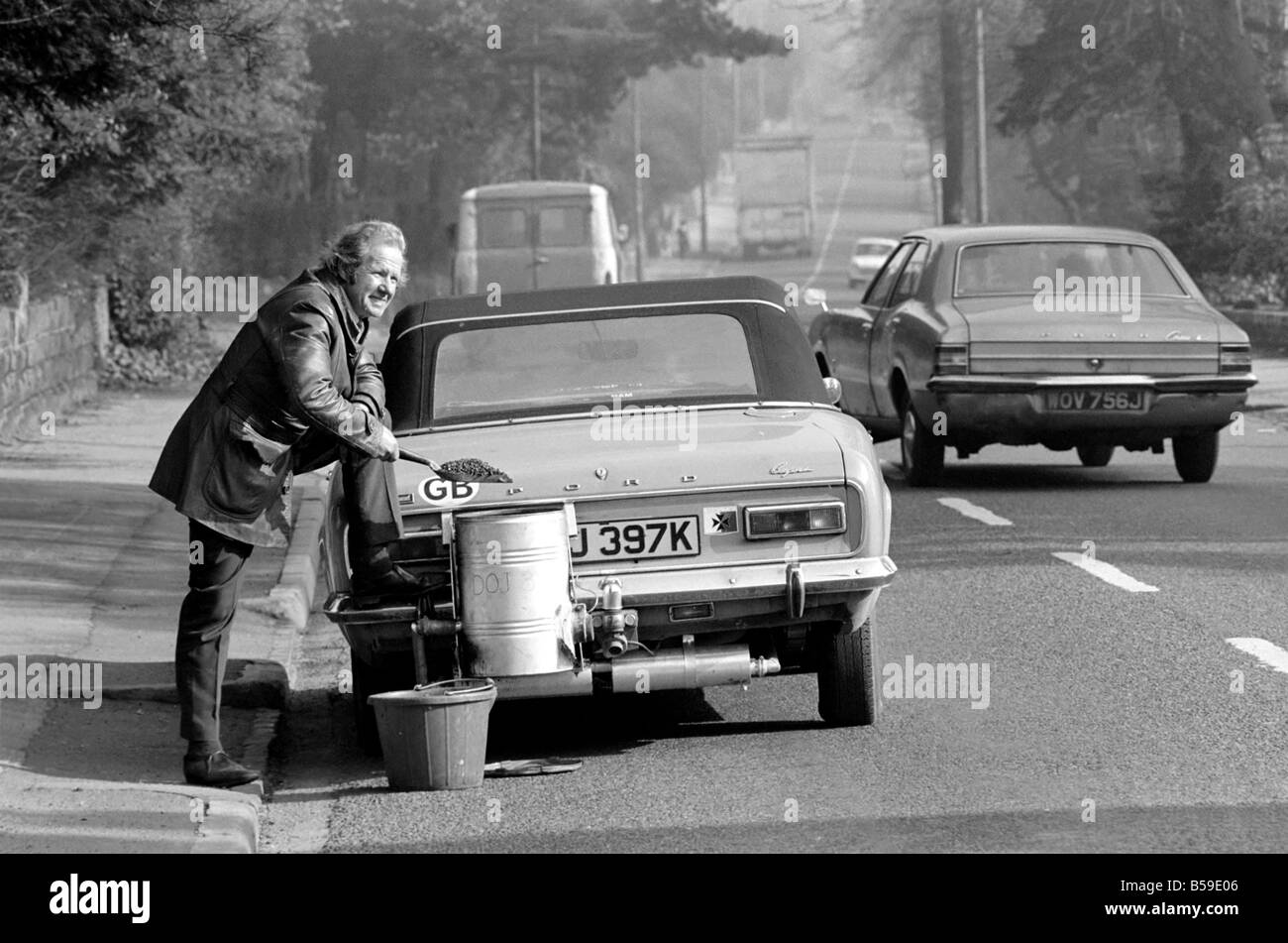 Mr. Douglas Purser who runs his Ford 1,600 c.c. Capri on Coal, is pictured shovelling anthracite into the burner. Feb. 1975 75-0 Stock Photo