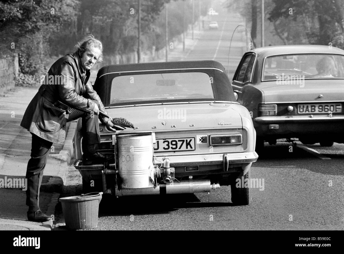 Mr. Douglas Purser who runs his Ford 1,600 c.c. Capri on Coal, is pictured shovelling anthracite into the burner. February 1975 Stock Photo