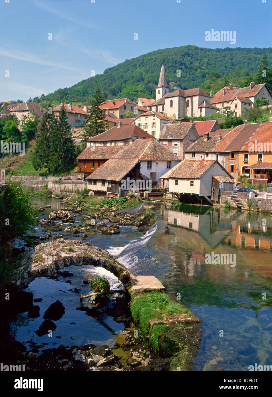 The weir and remains of a medieval bridge on the River Loue, houses and church of the village of Lods in Franche-Comte, France Stock Photo