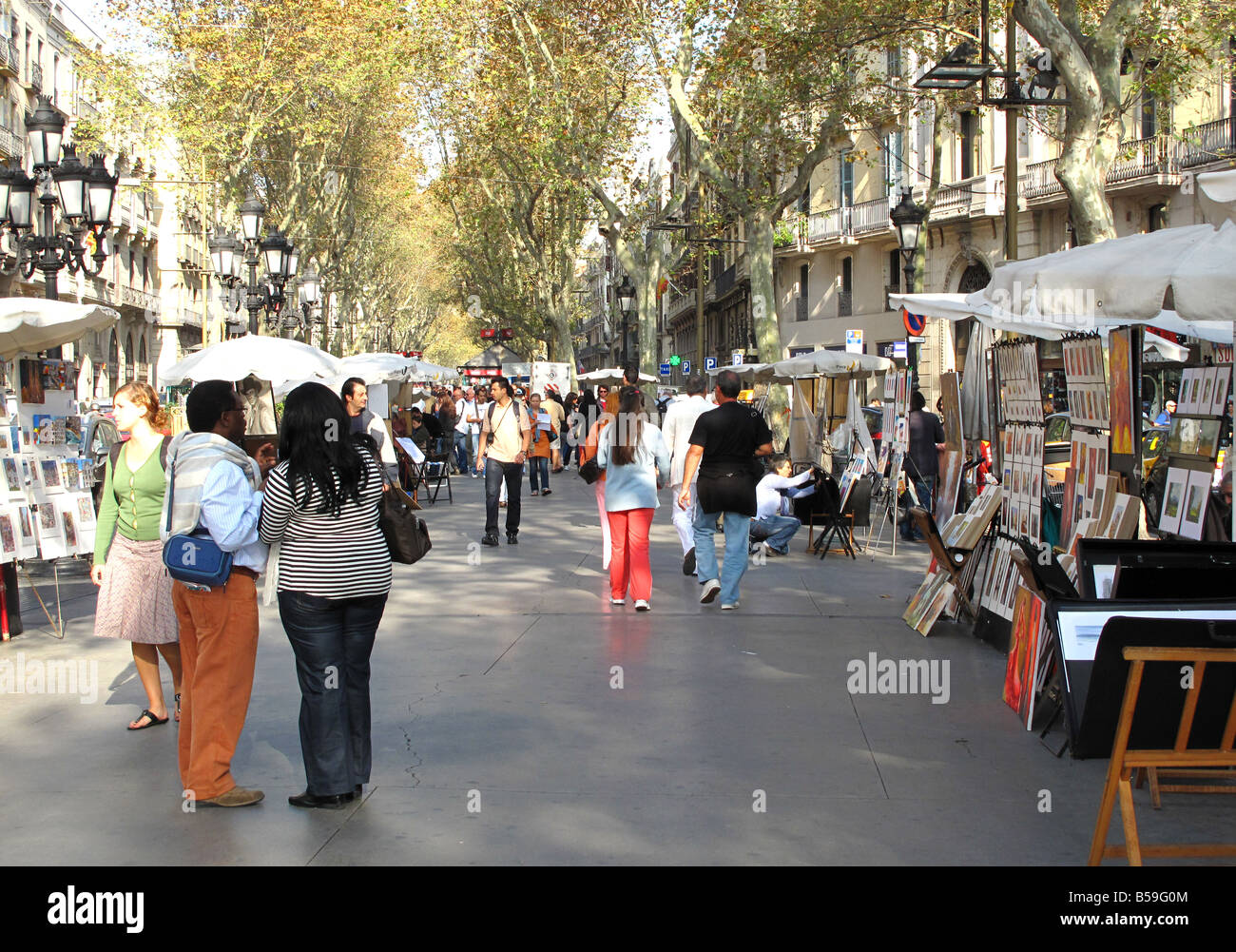 Tourists looking at street artists on a sunny day on La Rambla, Barcelona, Spain Stock Photo