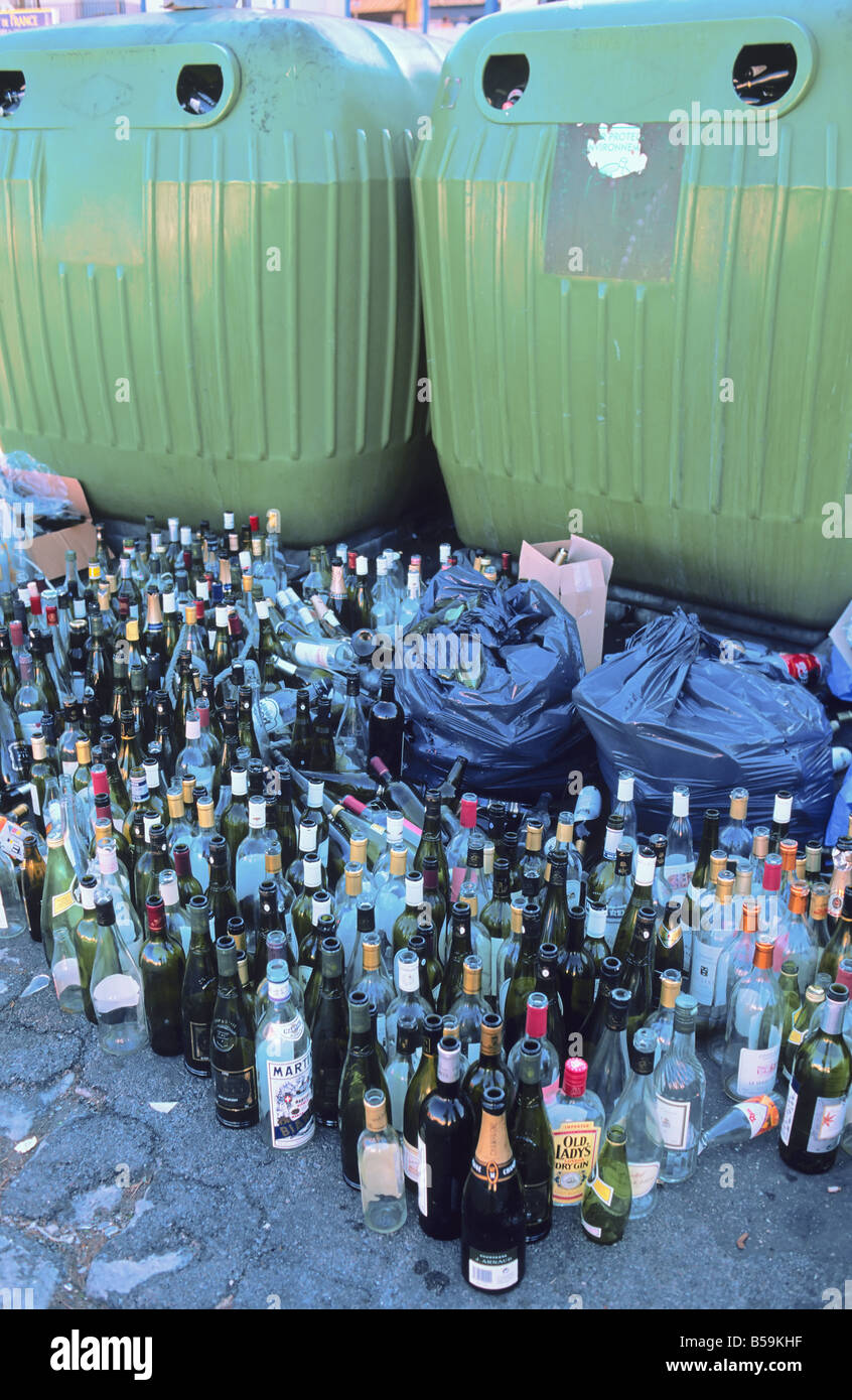 Empty glass bottles dumped in front of overflowing bottle banks, Sète