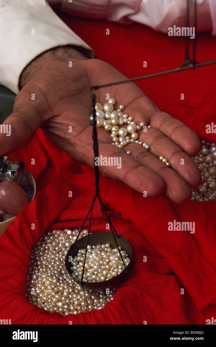 Closeup of hand displaying pearls with weighing scales, in the pearl