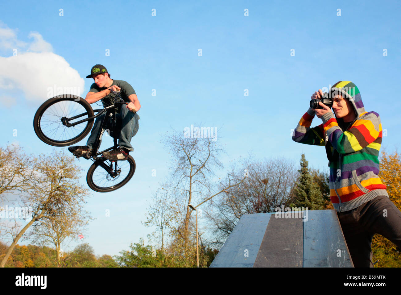 young man jumping with his bicycle while another one is taking photographs Stock Photo
