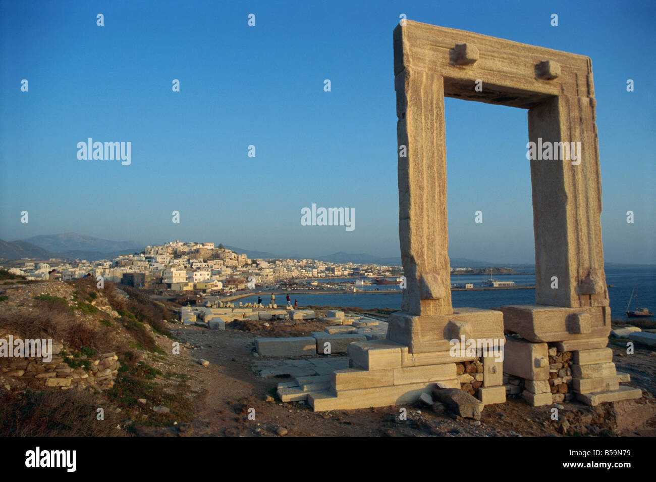 Roman arch at archaeological site with sea and village in the background, on Naxos, Cyclades Islands, Greek Islands, Greece Stock Photo