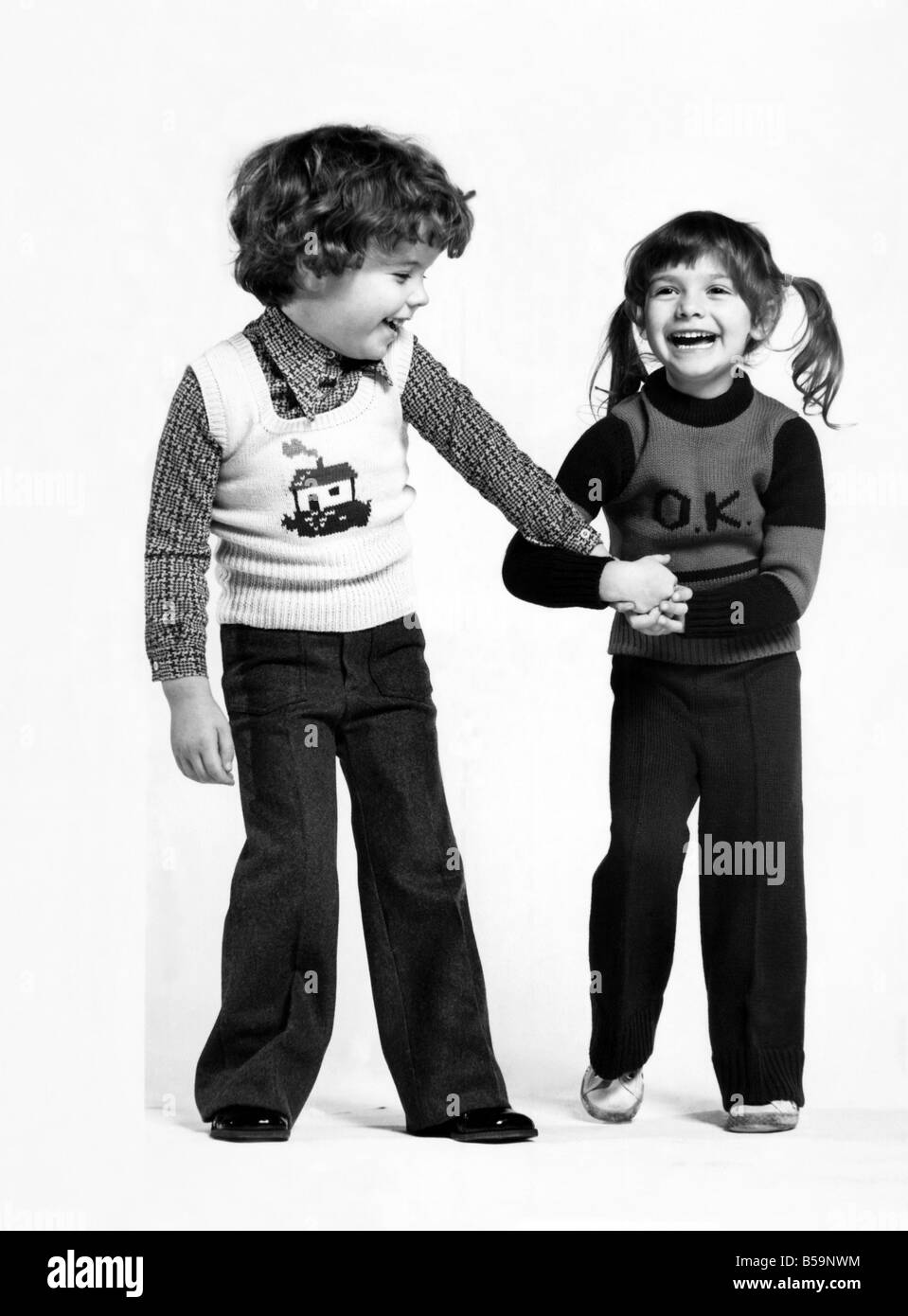 Mini-models Stephen and Tamara in some of the continental styles available from Zero Four. ;He wears flannel trousers, a check shirt and a sweater;Tamara wears sweater and knitted trousers ;November 1973 ;P007884 Stock Photo