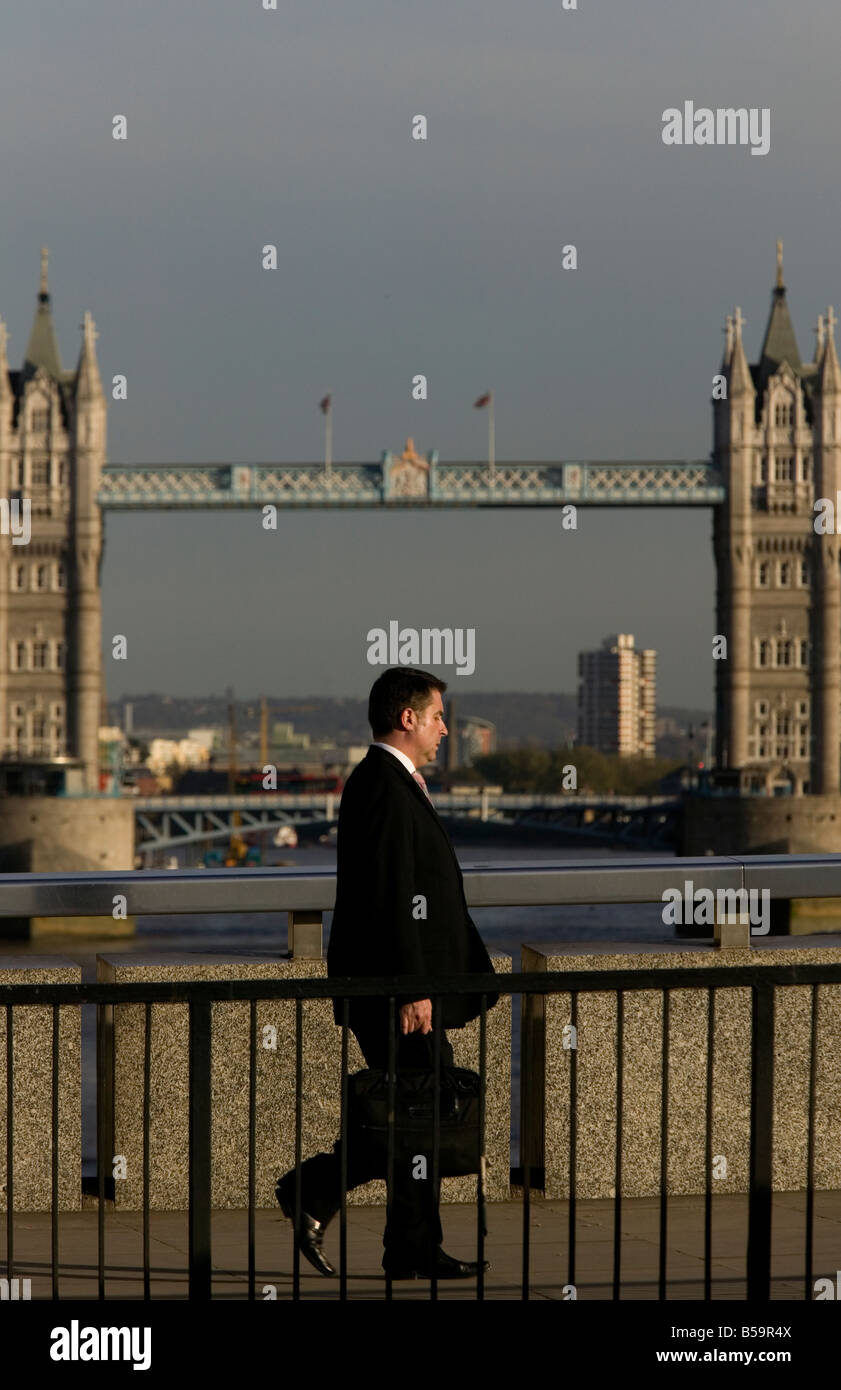 City of London worker walking across London Bridge Tower Bridge in background Stock Photo